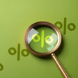 Magnifying glass focusing on a percentage symbol on a green background