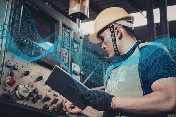 Person in a control room with industrial equipment and safety gear