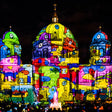 Colorful illuminated sculpture of a building with a dark background