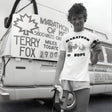 Person wearing a 'Marathon of Hope' shirt standing in front of a van with Terry Fox fundraising sign.