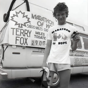 Person wearing a 'Marathon of Hope' shirt standing in front of a van with Terry Fox fundraising sign.