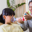 Person administering an inhaler to a child in a home setting