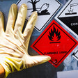 Hand wearing a yellow glove with flammable liquid warning sign